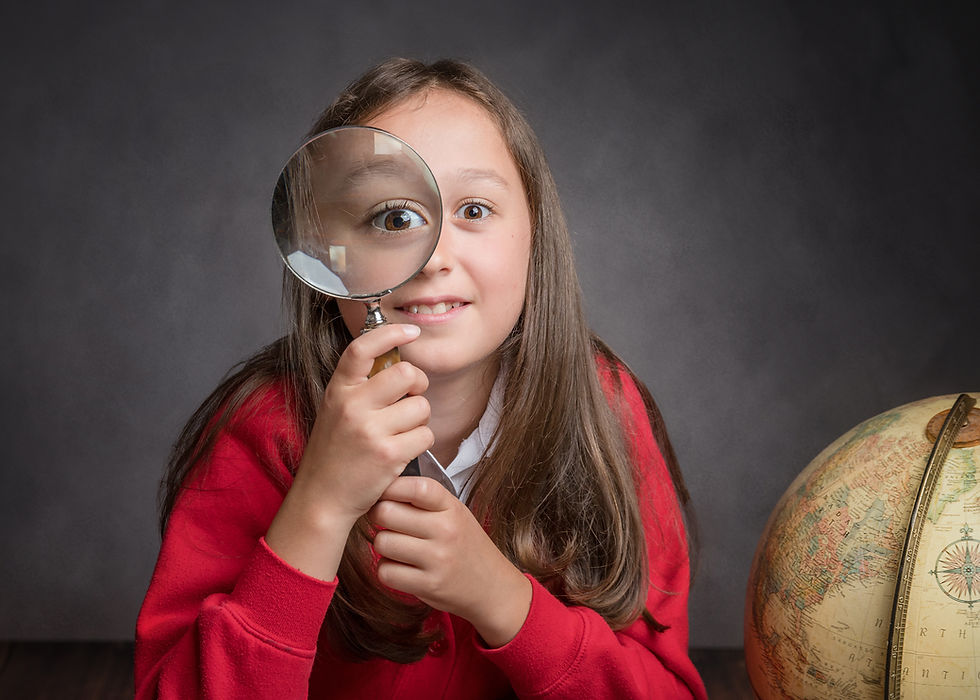 A school giril with St Peters Portishead uniform on. She is holding up a magnifying glass to her eye