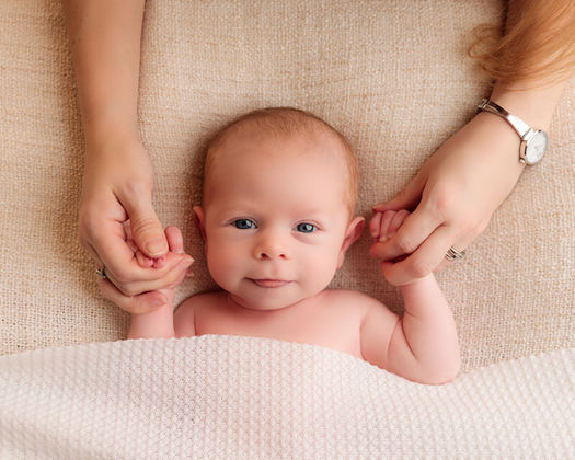 Newborn photography detail showing baby lying safely on a soft neutral background