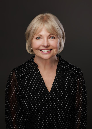 Professional studio headshot of a woman in Bristol with a relaxed, approachable expression on a dark background