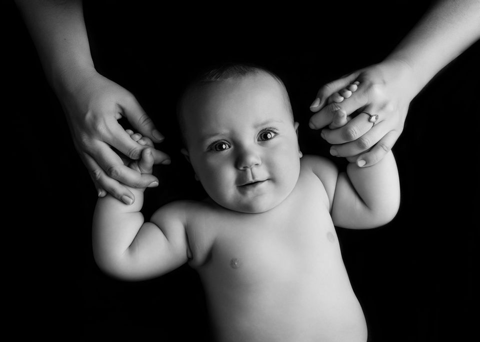 Black and white newborn portrait showing baby lying comfortably in a studio setting
