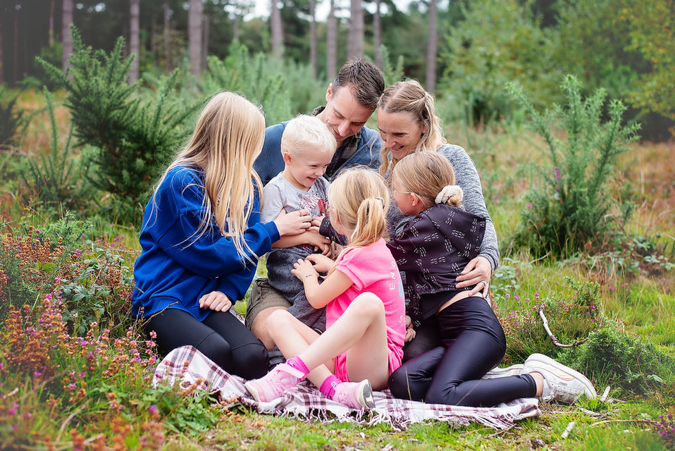 Extended family sitting together in woodland during a natural family photography session in Suffolk