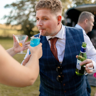 Groom enjoying drinks outdoors during a relaxed wedding reception