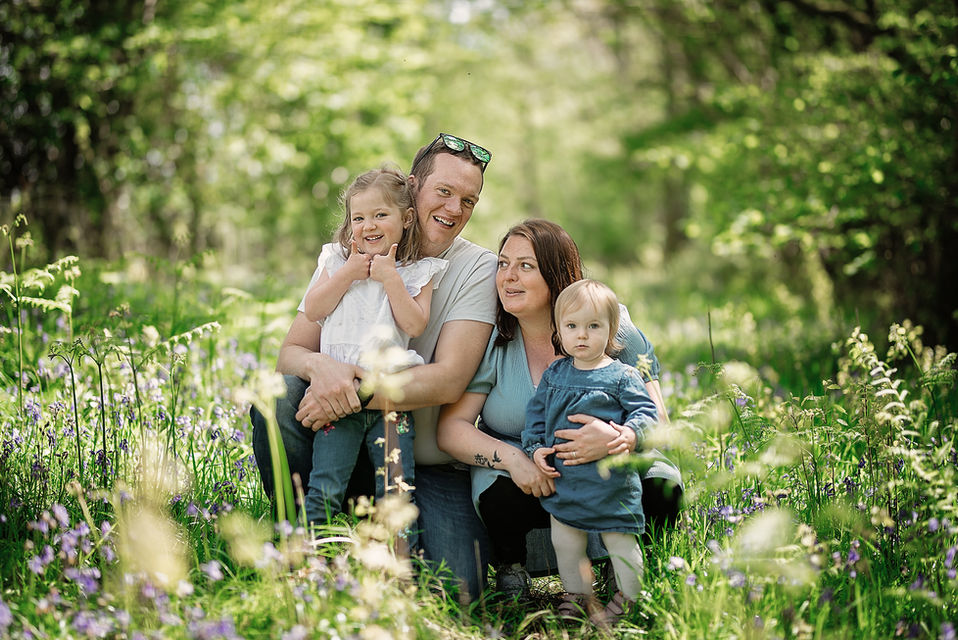 Family sitting together in wild grass during an outdoor lifestyle photoshoot in Suffolk