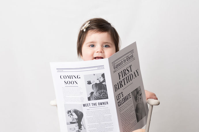 Baby holding a first birthday newspaper during a birthday photoshoot in Birmingham