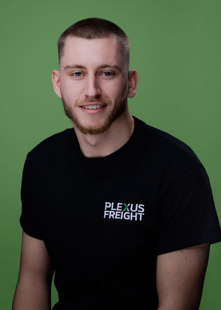 Modern corporate headshot of a male professional in a black t-shirt, clean studio portrait with a relaxed, contemporary business feel.