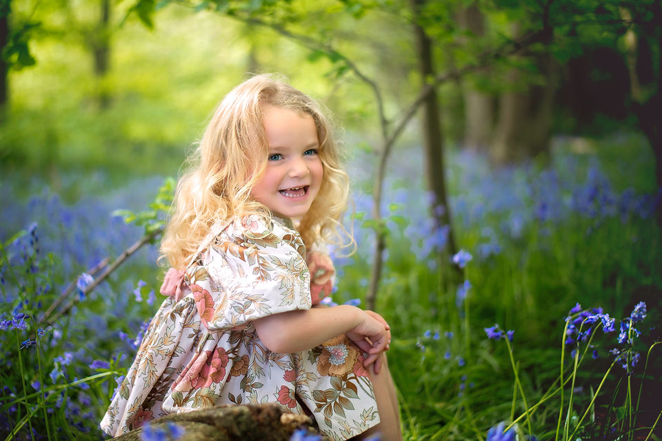 Young child smiling in bluebells during a spring family photoshoot in Suffolk