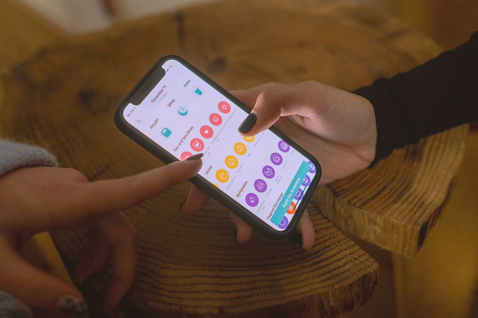 Hands interacting with a smartphone displaying a health app, showing various colorful icons on a wooden table. Dimly lit, focused scene.