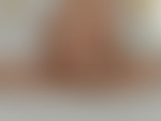 Person in pink pajamas sits cross-legged on a bed, holding a piece of paper. White bedding surrounds them, evoking a calm mood.