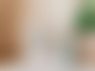 Frame with "Start each day with a grateful heart" text, next to a pale blue jug holding green leaves, on a light surface, brick wall behind.