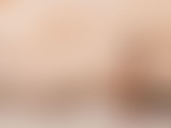 Woman in a floral dress stands on a sandy rock formation, gazing at the textured layers. Warm, earthy tones create a serene mood.