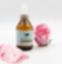 Tónico facial natural de rosas de Reverdecer junto a pétalos de rosa sobre fondo blanco