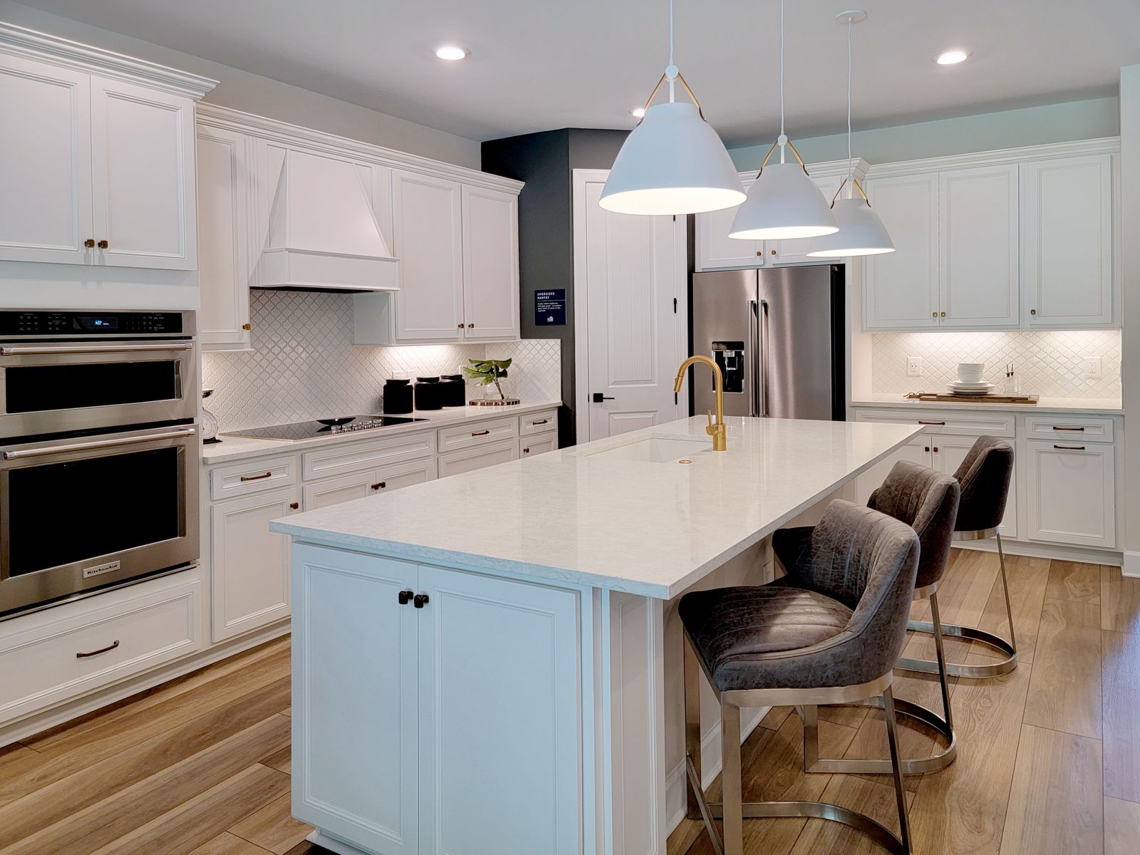 White kitchen with warm pendant, recessed and under-cabinet lighting — illustrative service photo