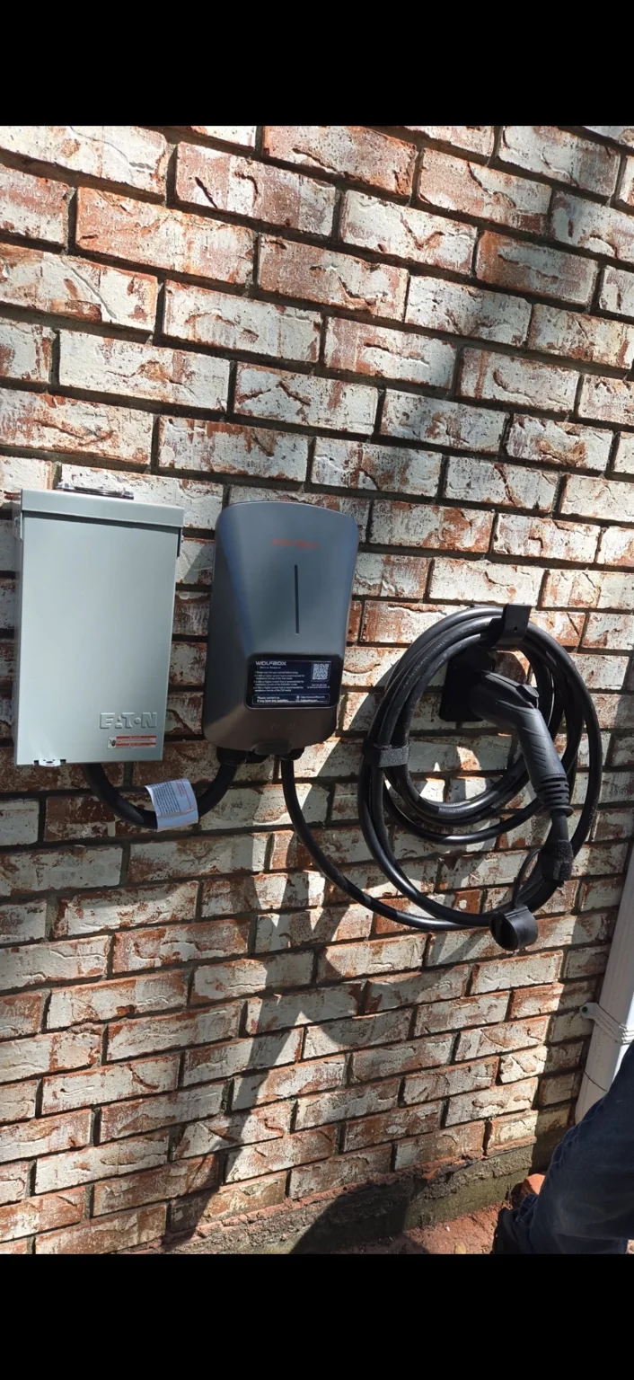 Outdoor EV charger. Charging equipment and disconnect mounted on an exterior brick wall.