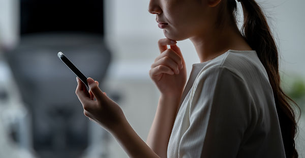 スマホを手に悩む女性