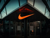 Well-lit orange Nike logo on a brick and mortar store.