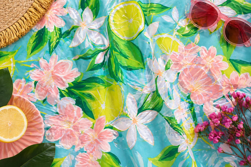 Tissu imprimé Limonata Fleurie avec fleurs blanches et rosées, feuillage vert et motifs citron sur fond bleu