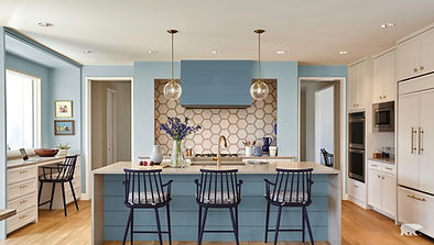 Updated kitchen with blue island, white cabinets, pendant lights, and bar seating