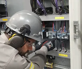 Eletricista industrial da Eletromantec realizando manutenção preventiva e testes em compon