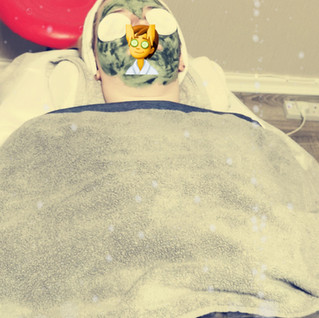 Woman lying on a beauty therapists bed having a facial