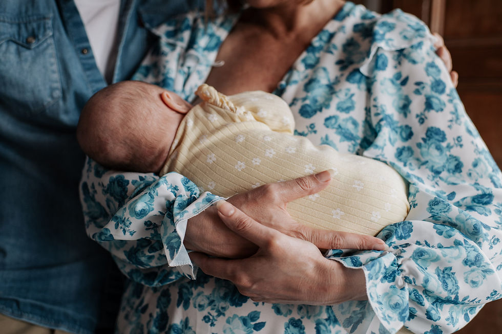 A woman in a floral blue blouse cradles a baby in a yellow blanket | Newborn photographer Newcastle | Angela Fenwick Photographer