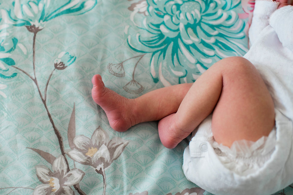 Baby's legs on a floral patterned teal blanket. The baby is wearing a white diaper. The scene feels soft and peaceful. Baby Photoshoot Durham | Angela Fenwick Photography