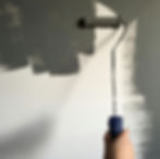 Ein Pinsel streicht eine Wand dunkelgrün