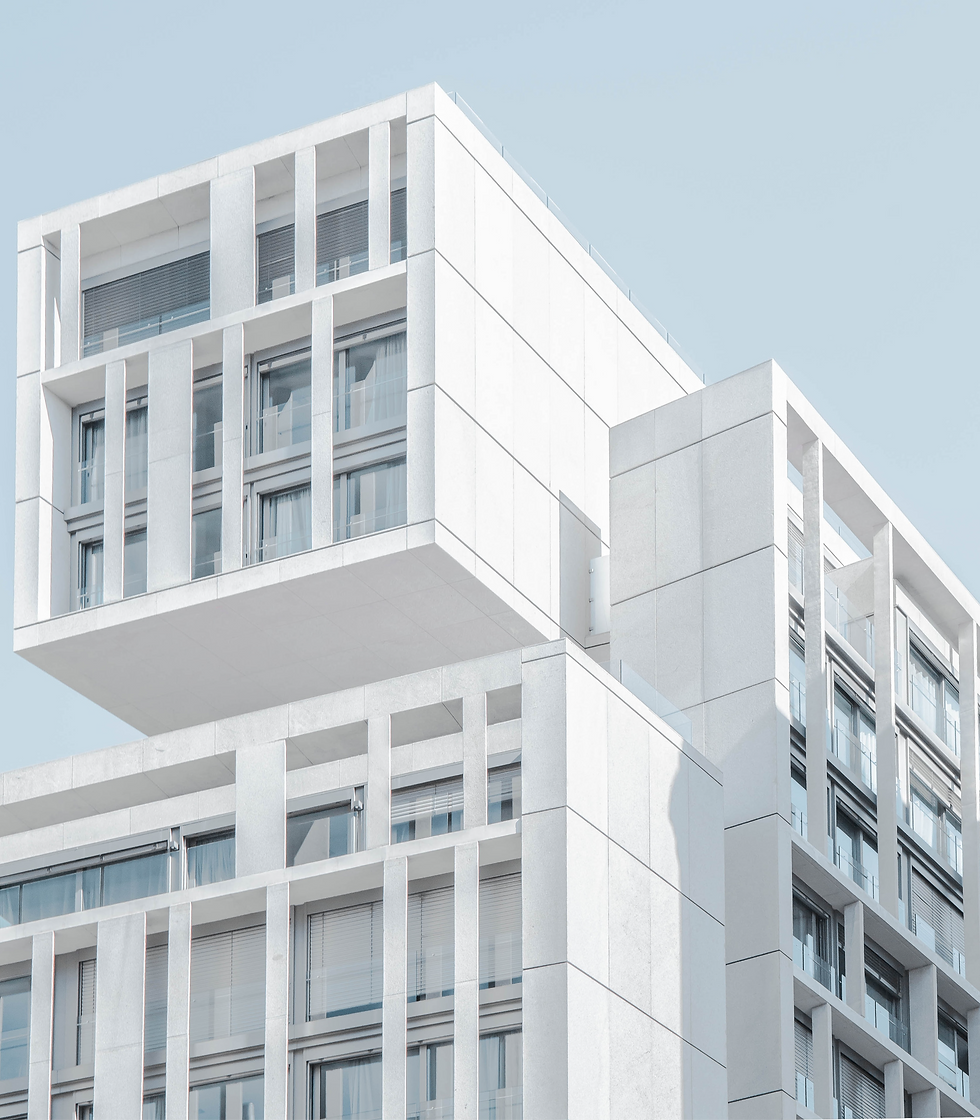Modern white building with geometric patterns against a clear blue sky. The structure features large windows and creates a minimalist vibe.
