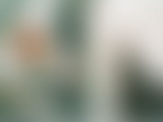 ine Person steht mit einem Tuch über den Schultern im Wasser, vor einer abstrakten Wand in Grün- und Brauntönen mit geometrischen Formen.