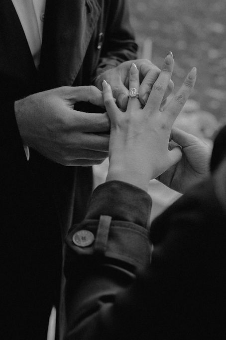 Close-up of groom placing diamond engagement ring on bride's finger during Central Park proposal, NYC