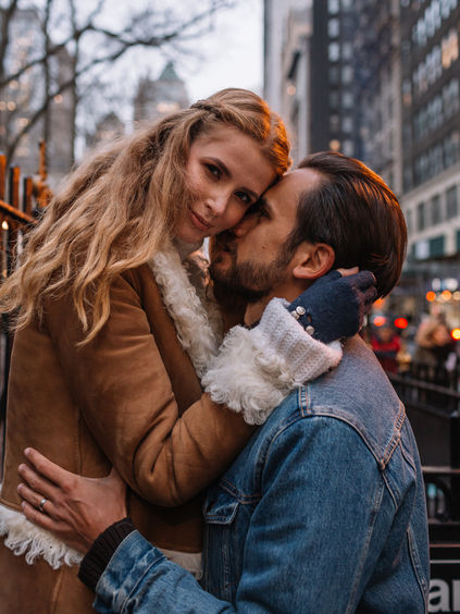 Couple embracing and kissing outside the Bryant Park subway station in December, NYC holiday couple shoot