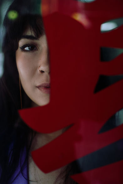 Artistic close-up portrait of a woman's face framed through a red Chinese neon character sign in NYC Chinatown