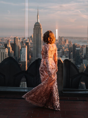 Back-view portrait of a woman in a sequin gown at Top of the Rock as the sun sets behind the Manhattan skyline, NYC