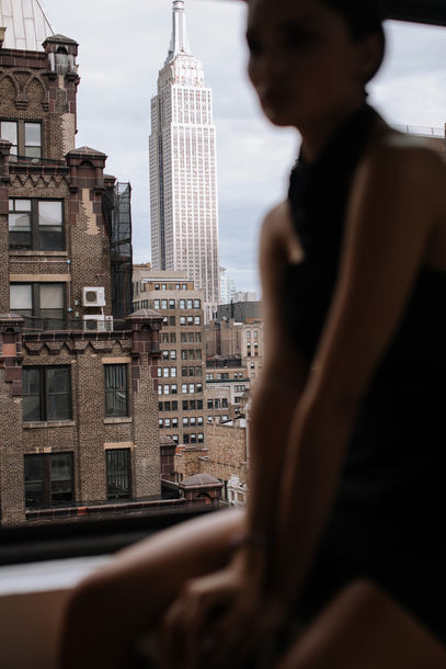 Moody silhouette portrait of a woman by a window with dramatic Empire State Building and Manhattan skyline view