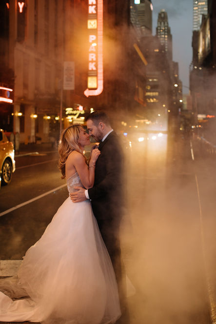 Couple kissing in steam on a glowing Midtown Manhattan street at night, warm golden neon light surrounding them, cinematic NYC wedding photo