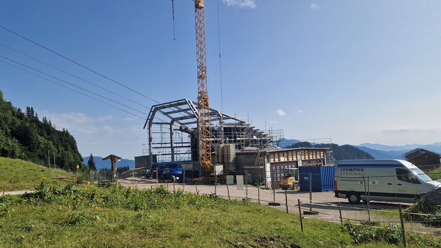 Baustelle in Berglandschaft mit Kran und entstehender Stahlkonstruktion