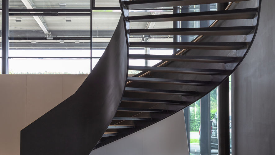 Untersicht einer geschwungenen Stahltreppe mit dunkler Stahlverkleidung im Innenraum