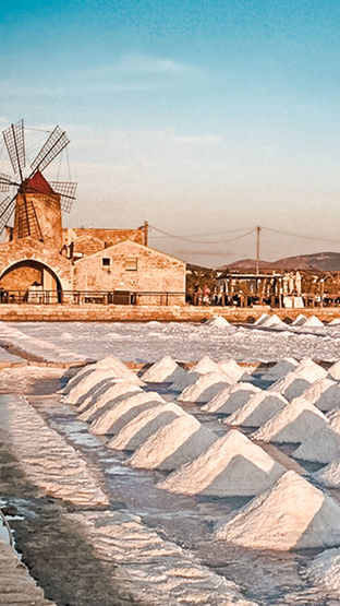 Saline di Marsala con mulino a vento storico al tramonto in Sicilia