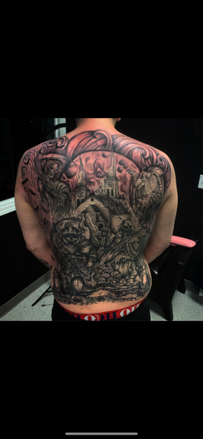 a man has a full back tattoo of a cemetery and a clock tower