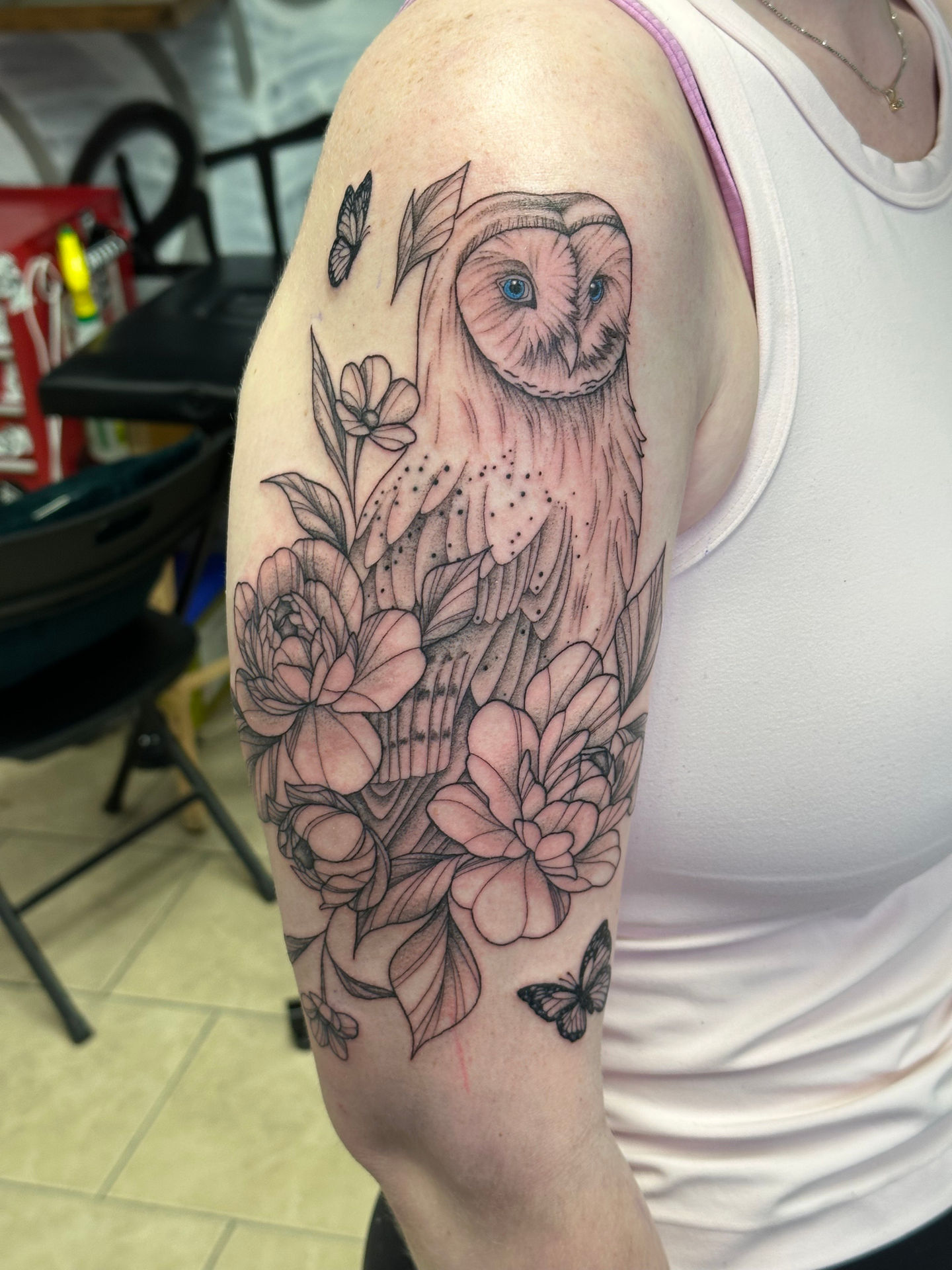 a woman has a tattoo of an owl surrounded by flowers and butterflies