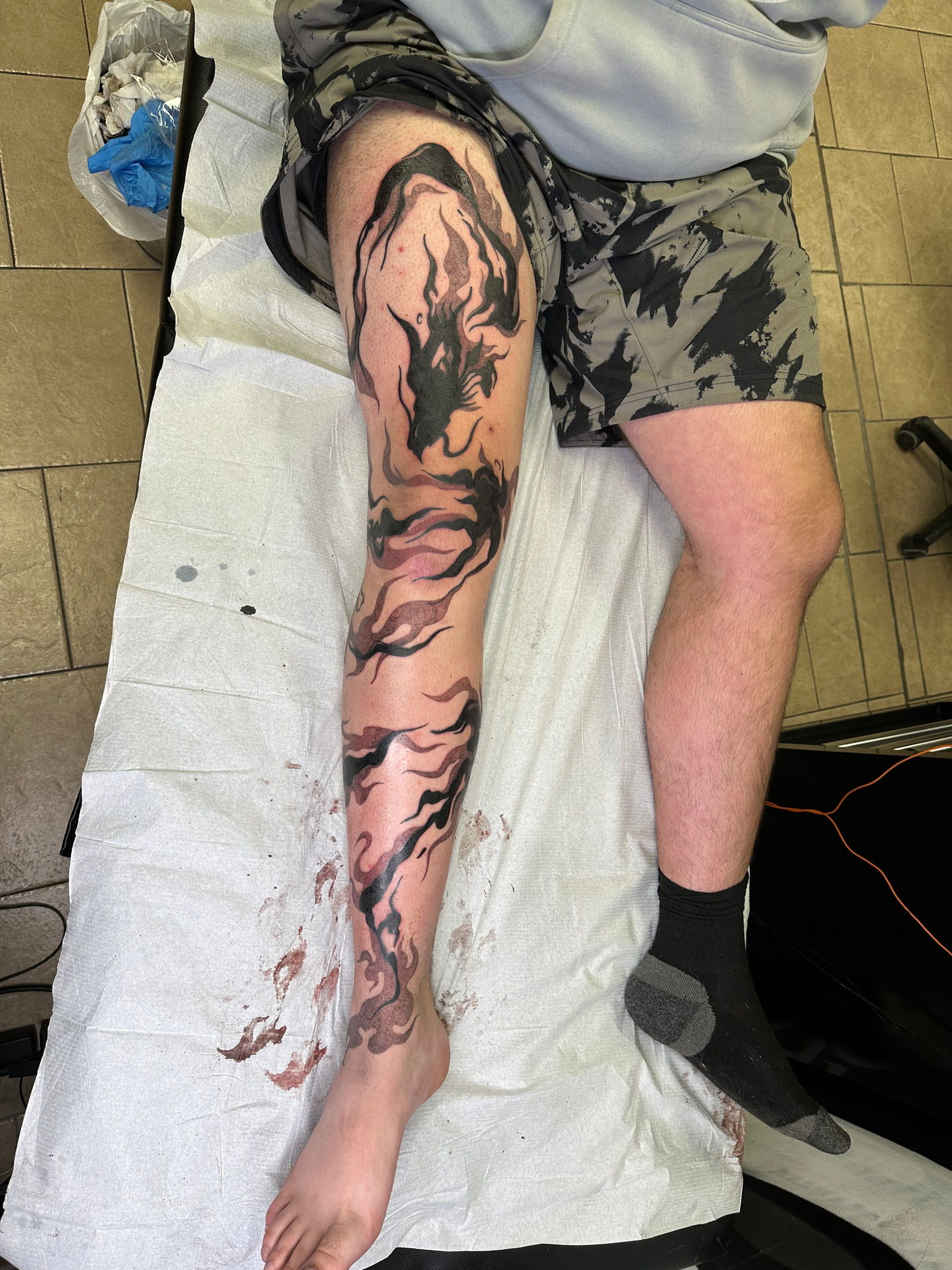 a person laying on a bed with a tattoo on their leg