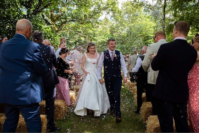 Bride and groom being showered with confetti after their ceremony on the family farm