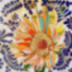 Colorful rainbow sunflower with gold-leaf center on a bright blue and white patterned background.