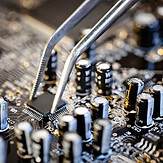 Computer motherboard being touched by tweezers