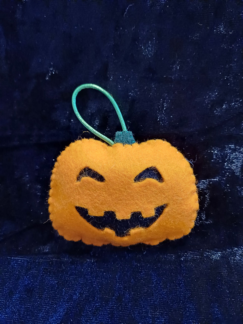 A grinning orange pumpkin decoration made from felt with green satin cord for hanging. 
