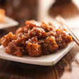 Delicious sesame chicken on a white plate with wooden chopsticks, Asian Supplies