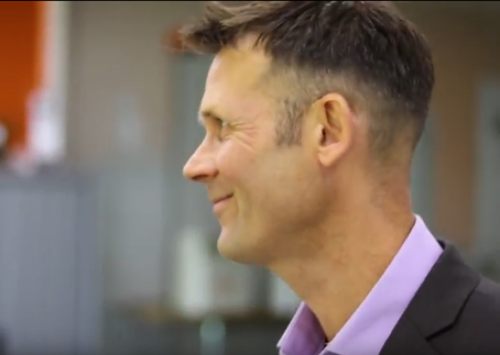 Smiling man in profile view, wearing suit, at a business conference About FB The Wholesaler