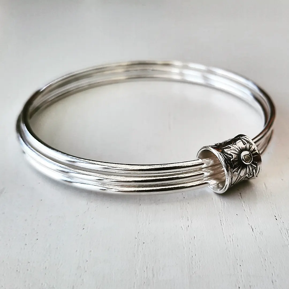 A Triple silver bangle with a flower textured ring