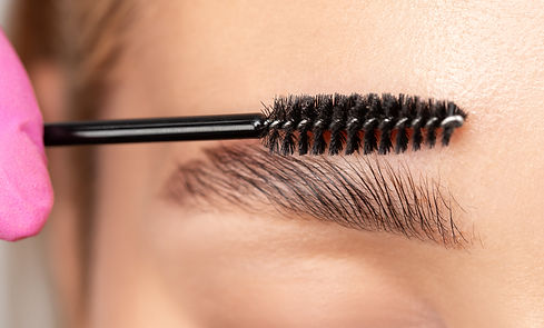 Makeup artist combs eyebrows with a brush after dyeing in a beauty salon. Professional mak