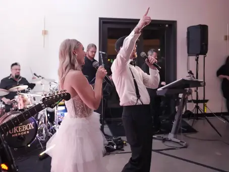 Bride and groom singing on stage with live wedding band The Jukebox Heroes