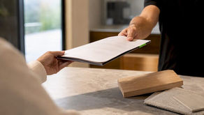 Builder handing homeowner contract folder